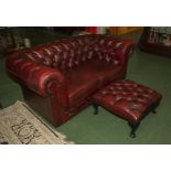 A red Chesterfield two seater sofa and foot stool