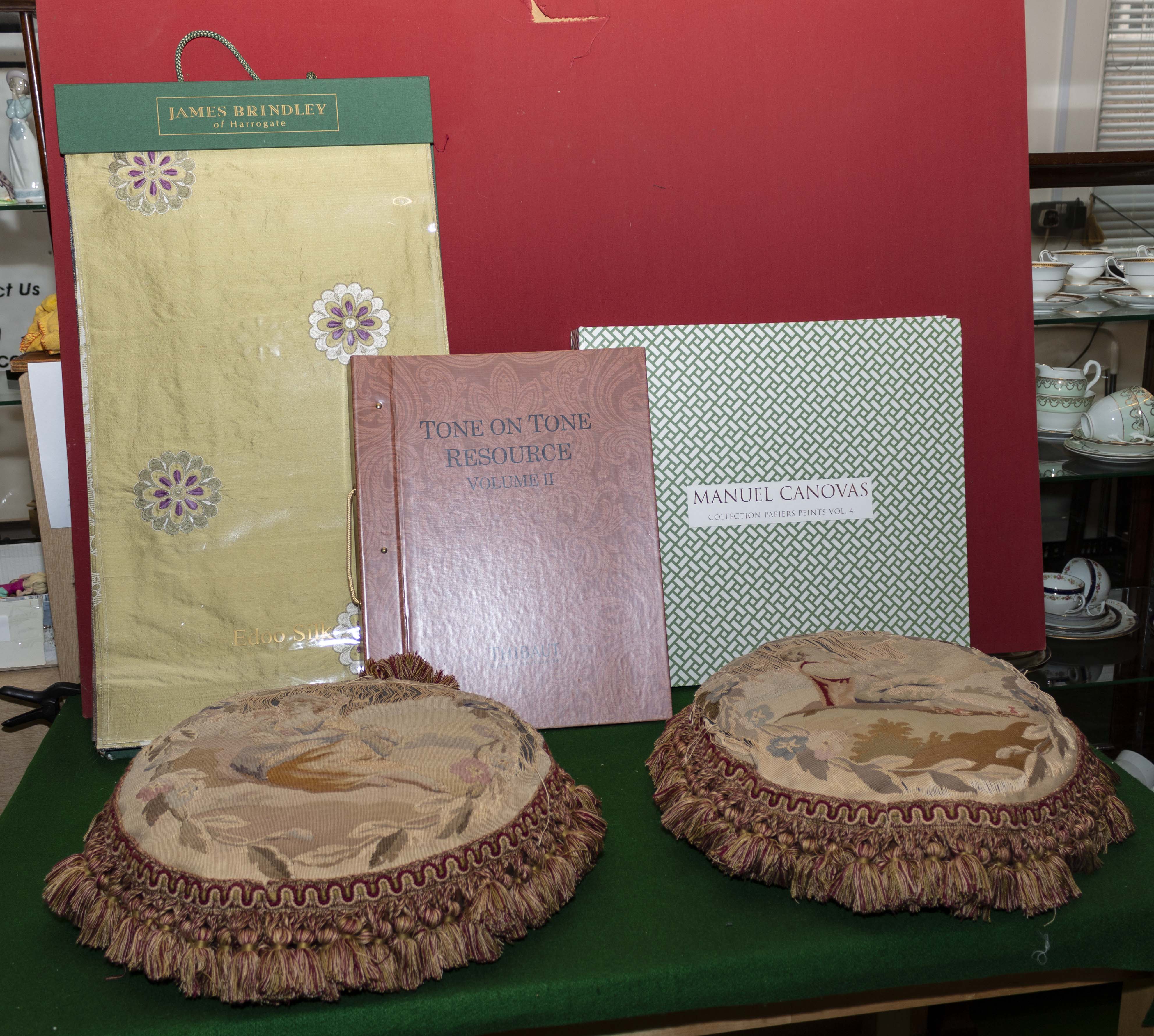 A silk fabric book, two wallpaper books and two cushions