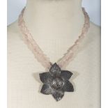 A rose quartz stone necklace with a silver pendant