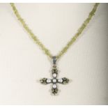 A peridot rough stone necklace with a silver cross set with pearls and peridot