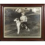Framed photograph of a little girl standing proudly with her champion greyhound. signed in ink to