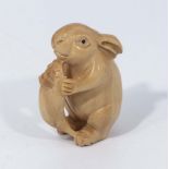 A hand carved hardwood netsuke of rabbit eating carrot