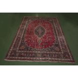 A red ground rug 8ft by 11ft 6inch.