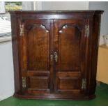 A period oak corner cabinet with shaped fielded panel doors