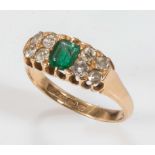 An 18ct gold ring set with an emerald and eight diamonds, size M