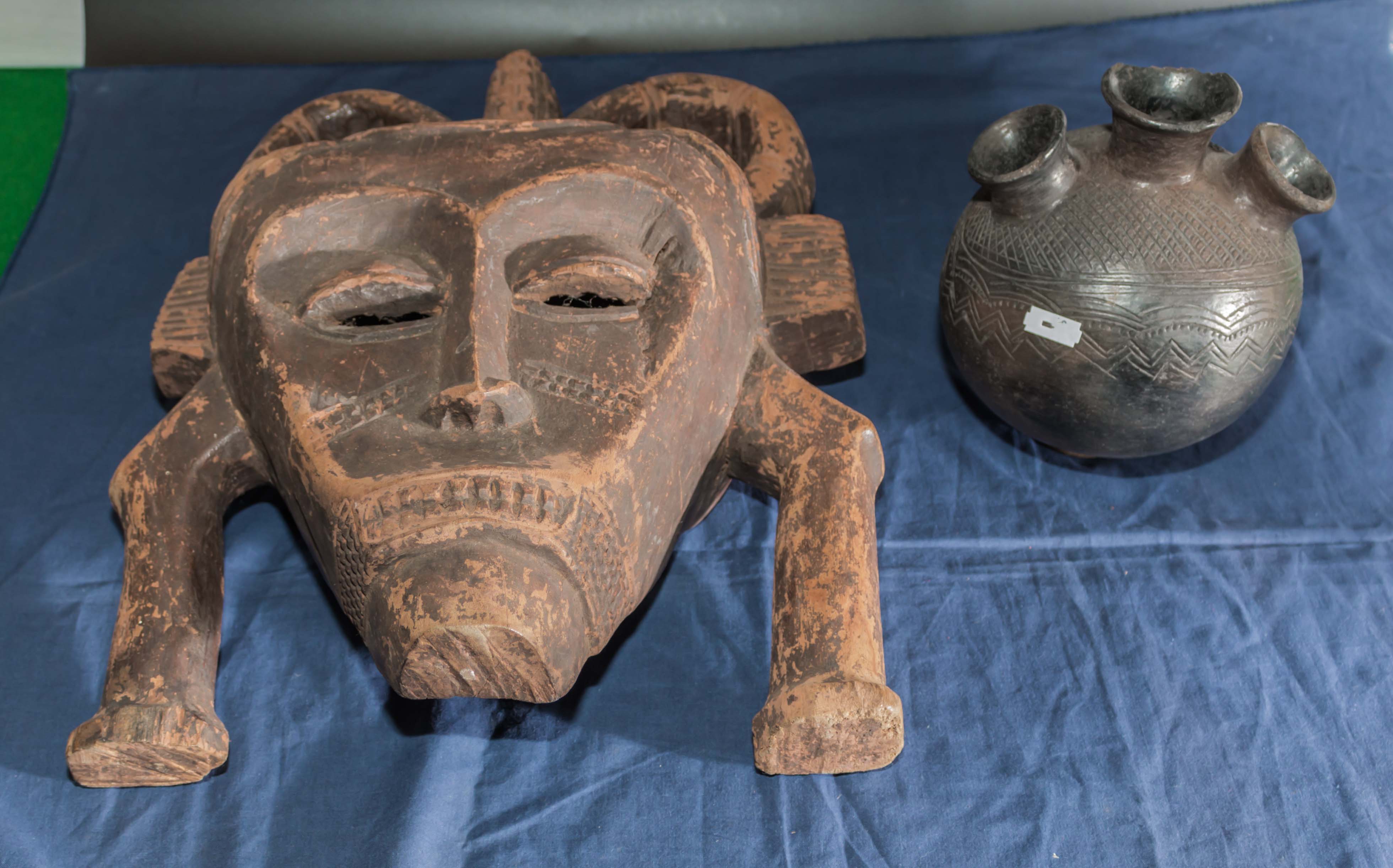 A carved African wooden mask together with a three necked bottle