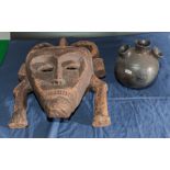 A carved African wooden mask together with a three necked bottle