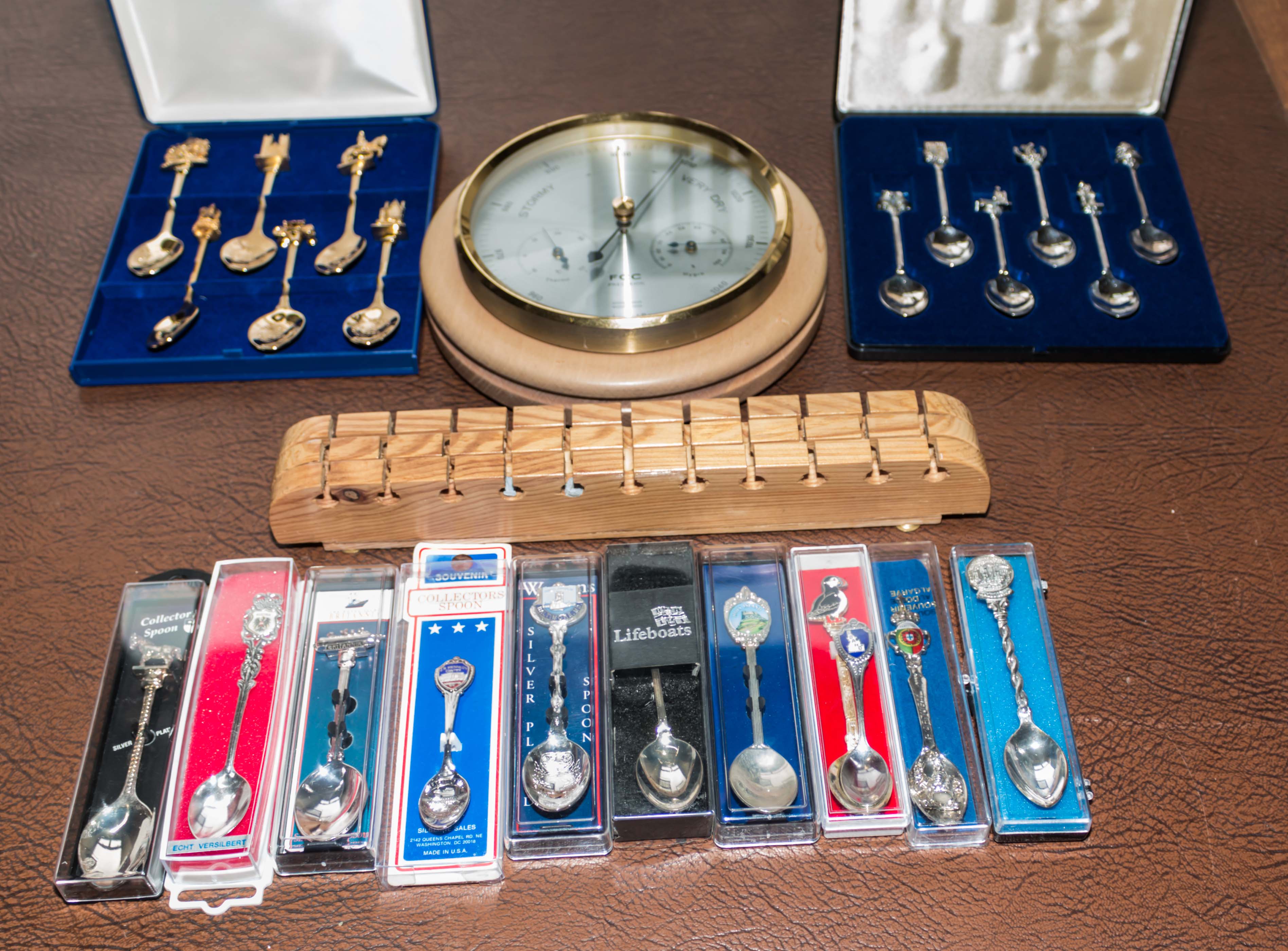 A collection of souvenir spoons and a barometer