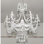 A white six branch chandelier with glass droppers