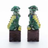 A pair of Chinese green and yellow glazed temple dogs on brown glazed bases