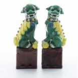 A pair of Chinese green and yellow glazed temple dogs on brown glazed bases