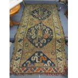 A Caucasian rug with twin medallions, S shaped and geometric motifs on a blue and beige ground,
