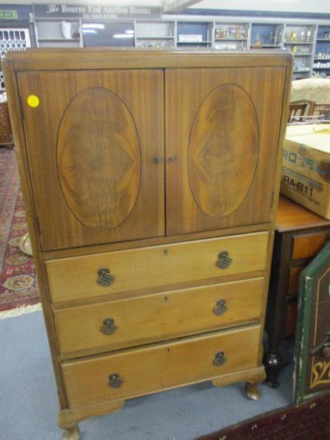 An early 20th century walnut side cupboard having twin doors, above three long drawers, on