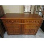 A mid 20th century light oak sideboard with two short drawers over twin cupboard doors