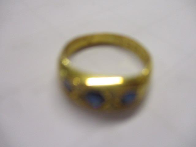 An early 20th century 18ct gold three stone sapphire and diamond chip ring