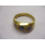 An early 20th century 18ct gold three stone sapphire and diamond chip ring