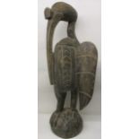 A large antique Polynesian carved, wooden bird with a long beak on a domed foot, 51" h