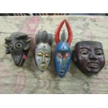 A group of four painted wooden African and Asian face masks