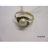 A yellow metal ring set with a central pearl flanked by two small sapphires, marks rubbed, total