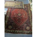 A Middle Eastern hand woven red ground rug with floral decoration and triple guard border, 59 1/2" x