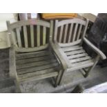 A pair of teak garden armchairs