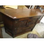 A reproduction oak side cabinet having carved panelled doors, a single drawer and a lower tier, 32