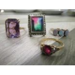 A group of four rings to include a yellow metal and amethyst ring, a 9ct gold and opal three stone
