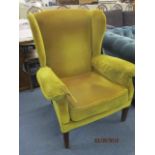 An early 20th century wingback armchair in mustard colour velour fabric, above mahogany square,