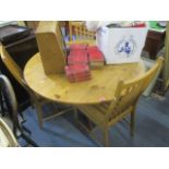 A modern pine circular topped dining table, 30" h x 47 1/2" w and a set of four Ercol chairs