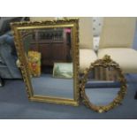 A contemporary gilt framed wall mirror with a rectangular glass plate and an oval gilt framed wall