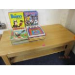 A modern beech coffee table and a selection of 1970s annuals to include Shoot, Dandy and others