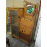 An Arts and Crafts oak bureau bookcase having a glazed door and fall flap, drawer and cupboard to