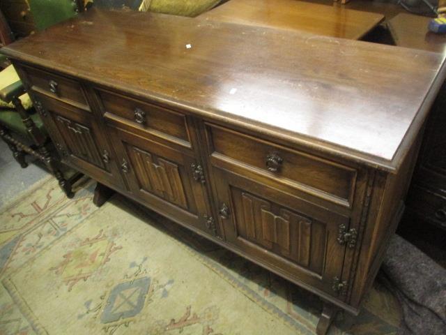 A reproduction oak linen fold sideboard having three short drawers and cupboard doors below, 34" x