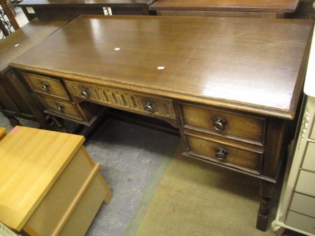 A reproduction oak desk having a central drawer flanked by four smaller drawers, 30" h x 50"w