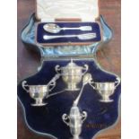 A silver condiment set with associated spoons, cased and a silver christening fork and spoon, cased