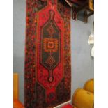 A Turkish hand woven rug with charcoal and red ground, geometric devices and styalized animal