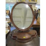 A Victorian mahogany swing mirror having an oval plate, carved decoration, the shaped base with