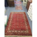 A group of four hand woven Persian and Turkish rugs, to include a red ground Bokhara rug with