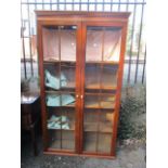 An oak glazed twin door tall bookcase standing on a plinth base 67 1/2"h x 38"w