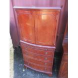 A reproduction mahogany bow fronted cabinet having twin doors above brushing slide and four