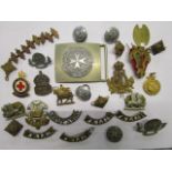 A selection of military cap badges, shoulder titles, buttons and other items