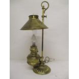 An early 20th century brass desk oil lamp with a scrolled handle, height adjustable shade and