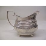 A George III silver cream jug London 1813, embossed and chased with birds, fruiting vines and banded