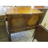 A reproduction mahogany cabinet with hinged top, two short drawers below standing on square