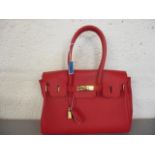 An Italian red leather fashion bag in the style of a Birkin bag
