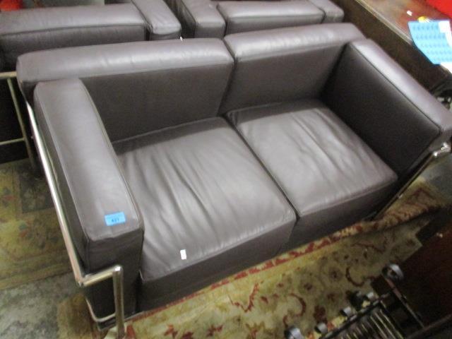 A brown leather two seater sofa with a chrome frame and two matching armchairs