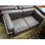 A brown leather two seater sofa with a chrome frame and two matching armchairs