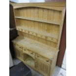 A modern pine dresser having a plate rack above three drawers and twin cupboard doors 74"h x 59"w