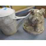 An outdoor stone model of a pig, together with an aluminium watering can