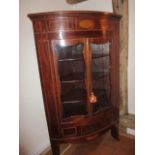 A Georgian mahogany inlaid corner cabinet with a pair of glazed doors above a small central